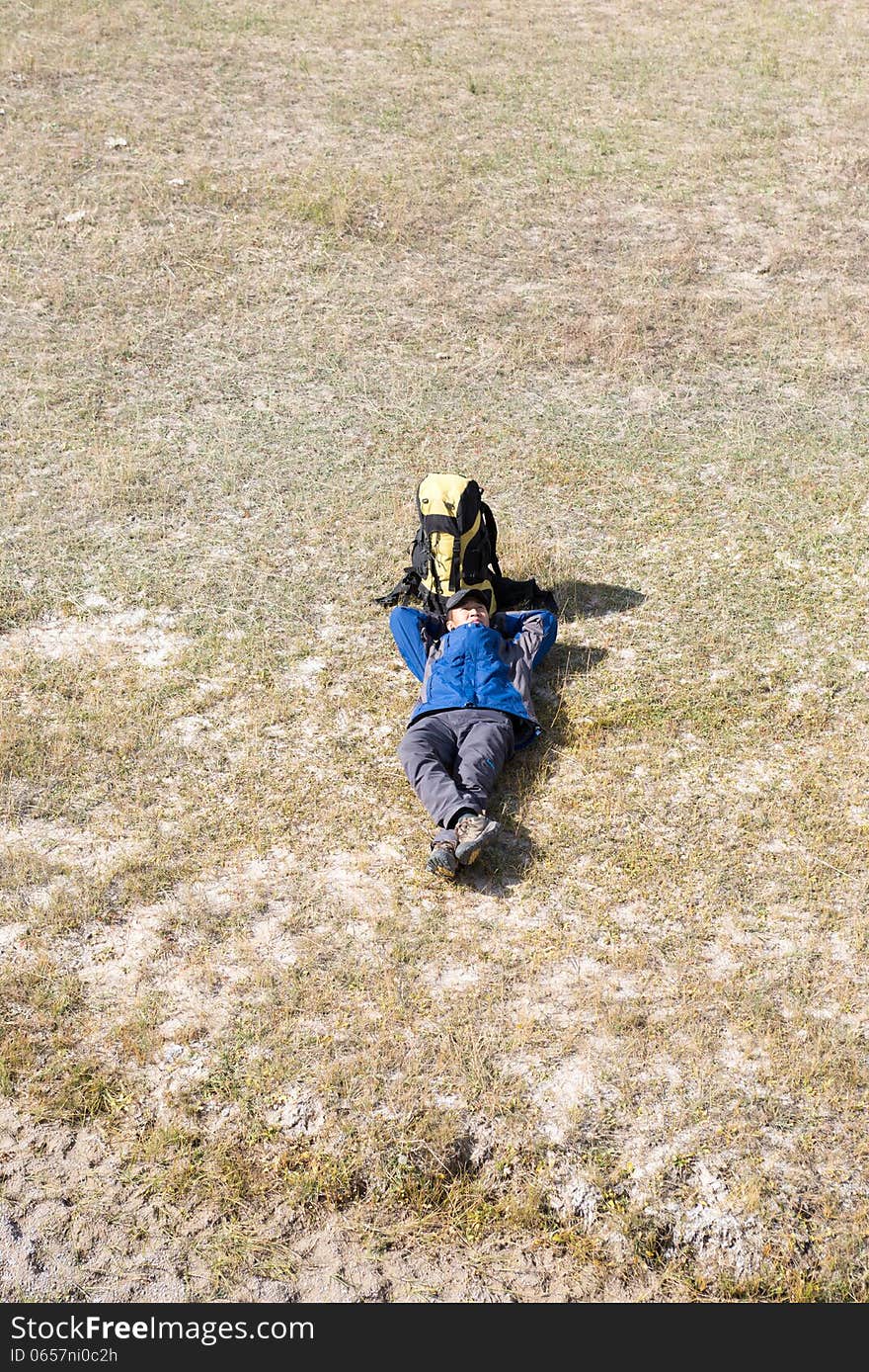 Hiker resting on the grass in autumn sunlight. Hiker resting on the grass in autumn sunlight