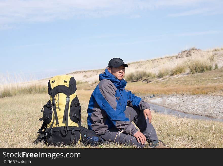 Hiker resting on the grass in autumn sunlight. Hiker resting on the grass in autumn sunlight