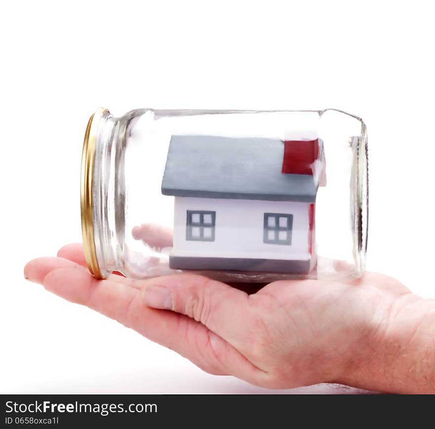 Property insurance. metaphor. mans hand carefully holding toy house model in a closed glass jar