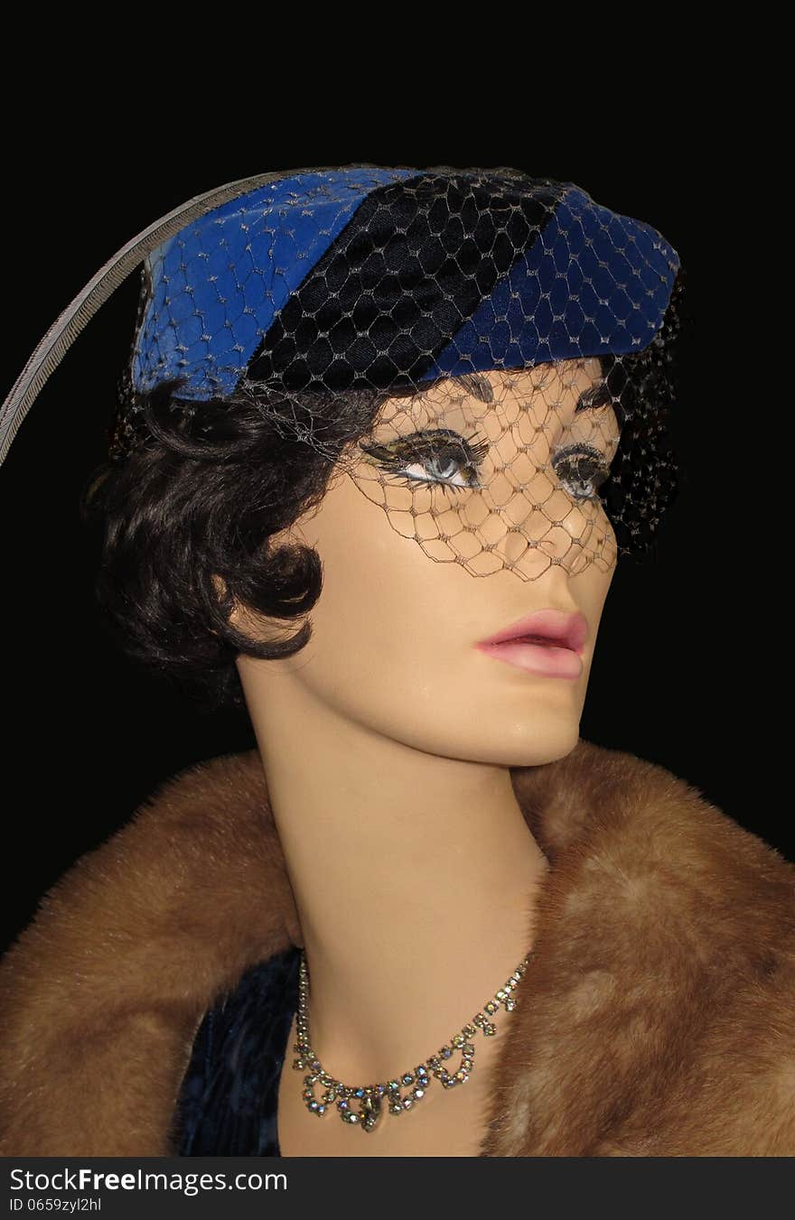 Woman mannequin dressed in vintage clothes from the 1940’s with veiled hat, mink stole, and necklace. Isolated on black. Woman mannequin dressed in vintage clothes from the 1940’s with veiled hat, mink stole, and necklace. Isolated on black.