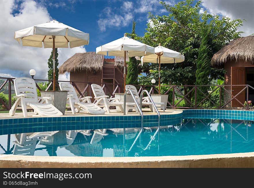 Swimming pool with sunbeds surrounded by tropical plants