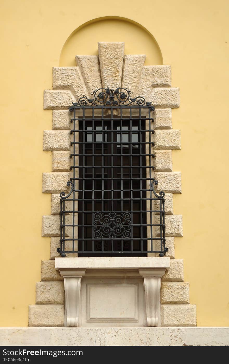 Window in Verona with features and forged metal bars on the wall yellow house