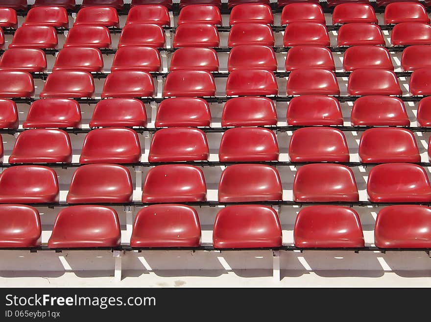 Amphitheater of red seats abstract background in sunlight. Amphitheater of red seats abstract background in sunlight