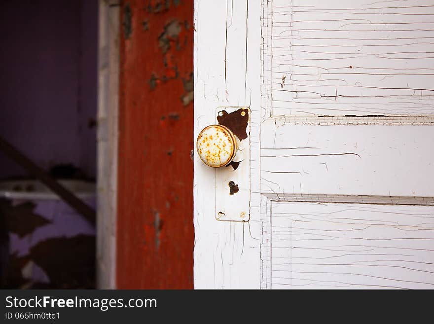 A white rusty doorknob on a white door