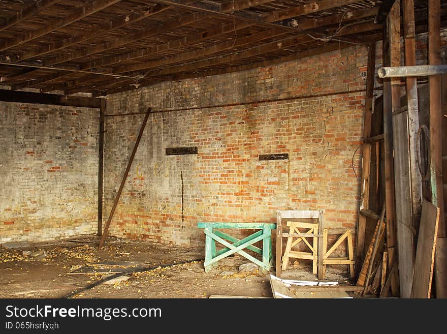 A weathered orange and yellow brick wall and a sawhorse in a abandoned building. A weathered orange and yellow brick wall and a sawhorse in a abandoned building