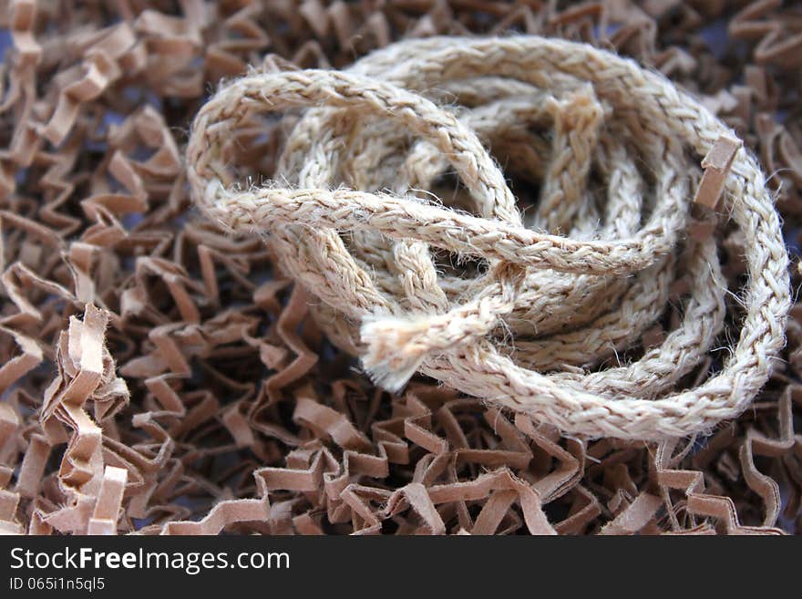 A piece of twisted hemp rope on background of textured material. A piece of twisted hemp rope on background of textured material