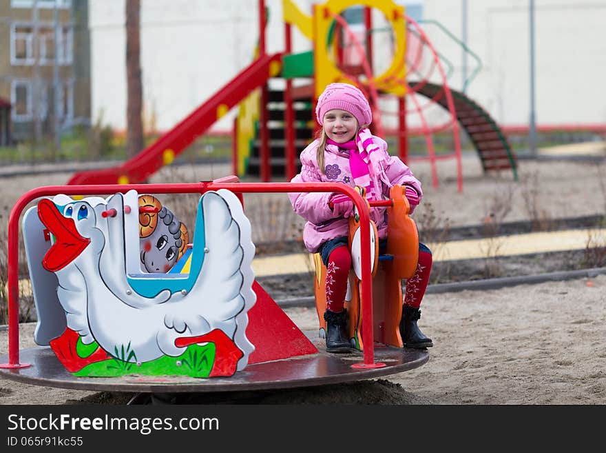 Little girl on the carousel in the autumn clothes