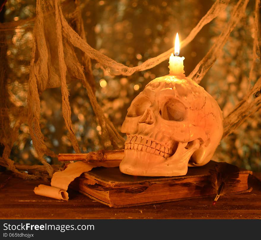 Creepy human skull with burning candle on old book. Creepy human skull with burning candle on old book