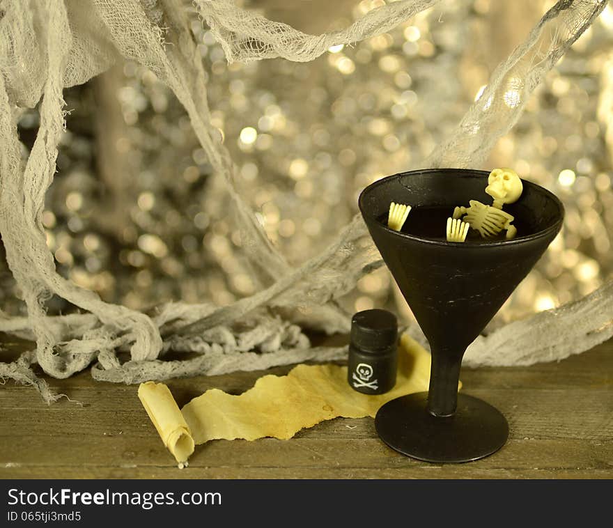 Skeleton in black cup of wine with poison and scrap of paper. Skeleton in black cup of wine with poison and scrap of paper