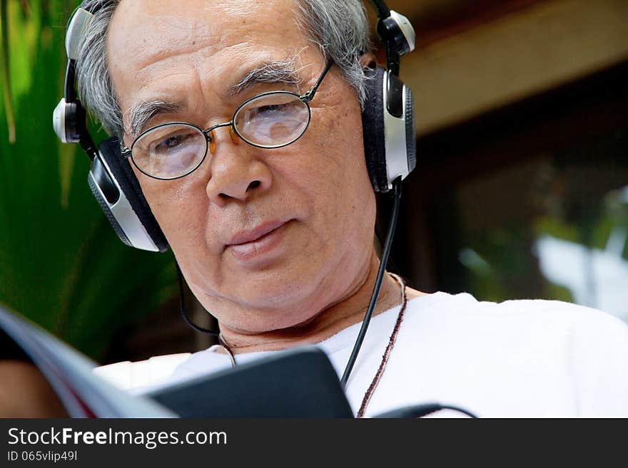 Senior man enjoying music on his tablet