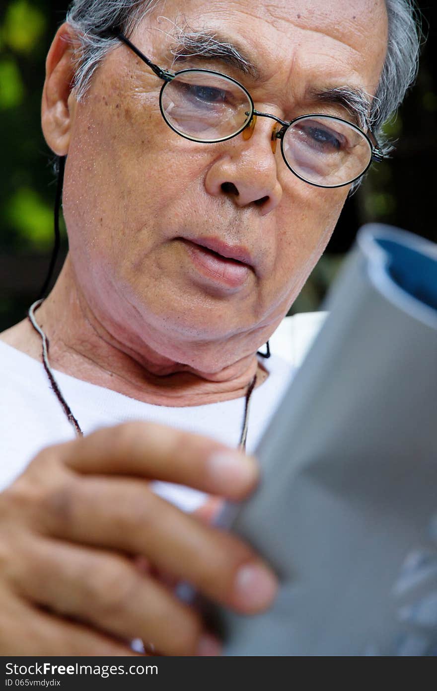 Senior man sitting outside reading a book