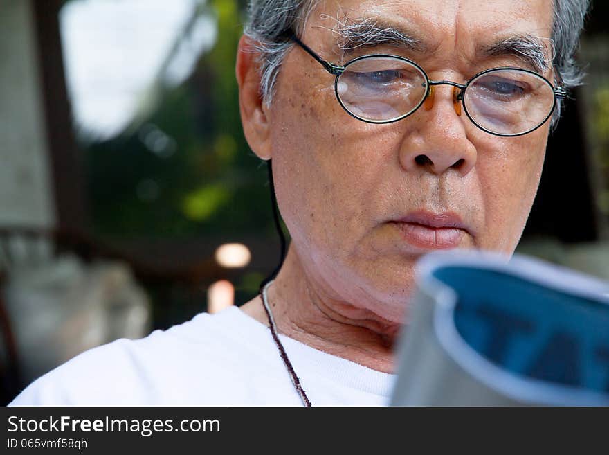 Image of senior man relaxing at home reading a book