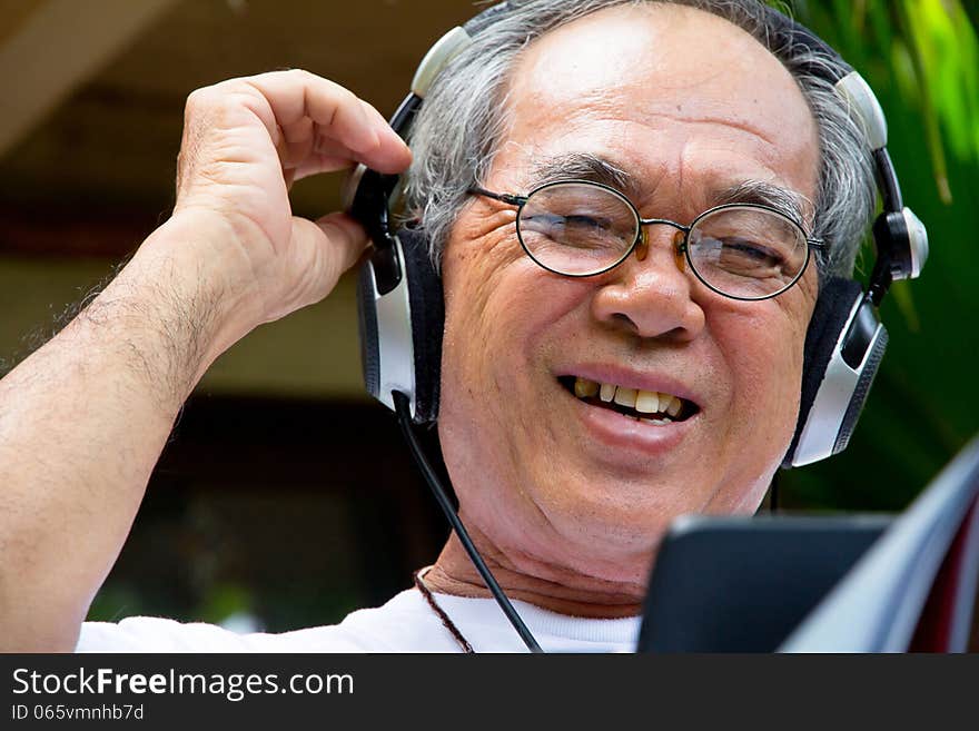 Senior man enjoying music on his tablet