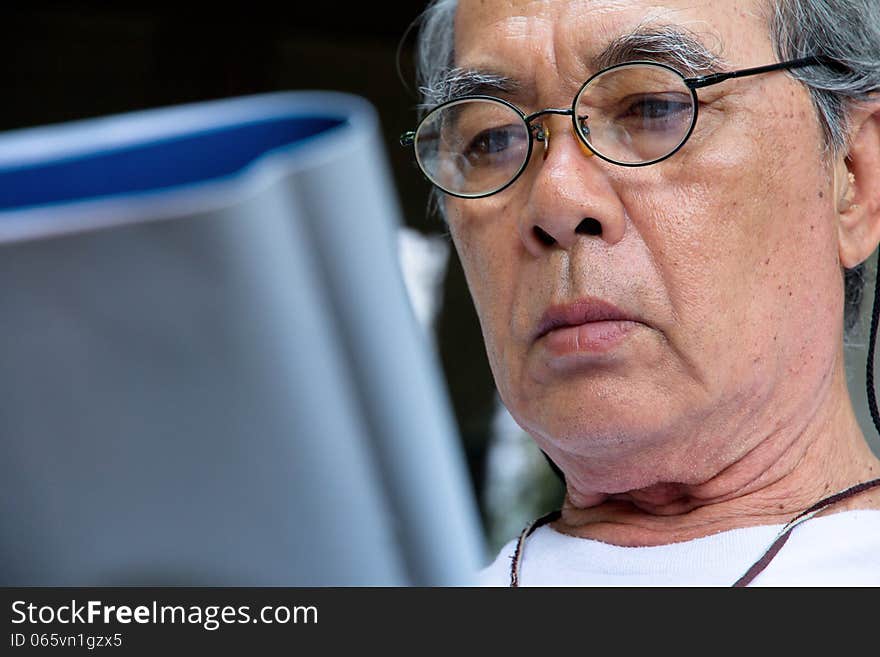 Image of Senior man relaxing at home reading a book