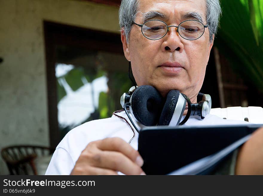 Senior man relaxing at home reading E-book on his tablet