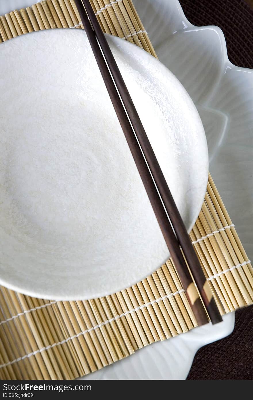 White dish with chopstick on bamboo mat. White dish with chopstick on bamboo mat