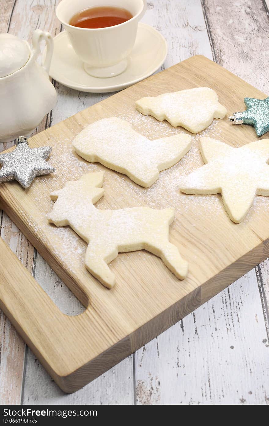 Homemade Christmas shortbread biscuit cookies in reindeer and festive shapes with a cup of tea on vintage blue and white shabby chic table. Homemade Christmas shortbread biscuit cookies in reindeer and festive shapes with a cup of tea on vintage blue and white shabby chic table.