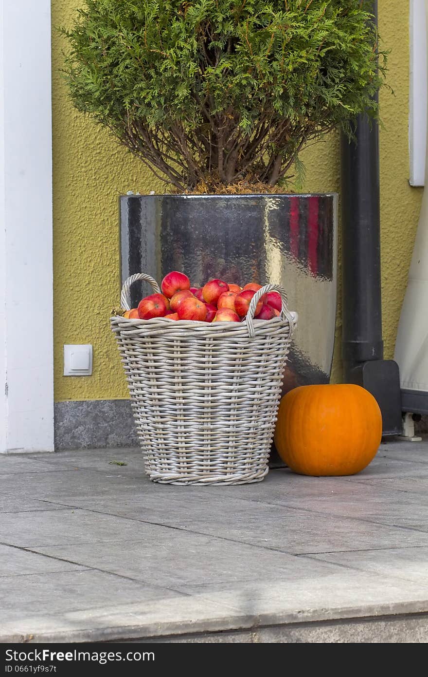 Apples in a basket with a pumpkin on the steps outside the building. Apples in a basket with a pumpkin on the steps outside the building