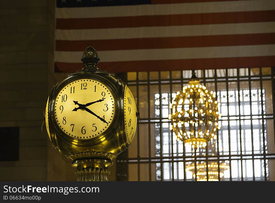 Detail of the antique gold clock over the Information Booth at Grand Central Station in New York City, with partial American flag in the background. Detail of the antique gold clock over the Information Booth at Grand Central Station in New York City, with partial American flag in the background.