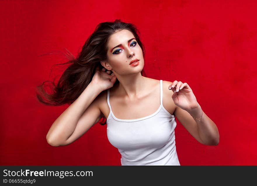 Girl with flying hair and colorful eyeshadow on red background. Girl with flying hair and colorful eyeshadow on red background