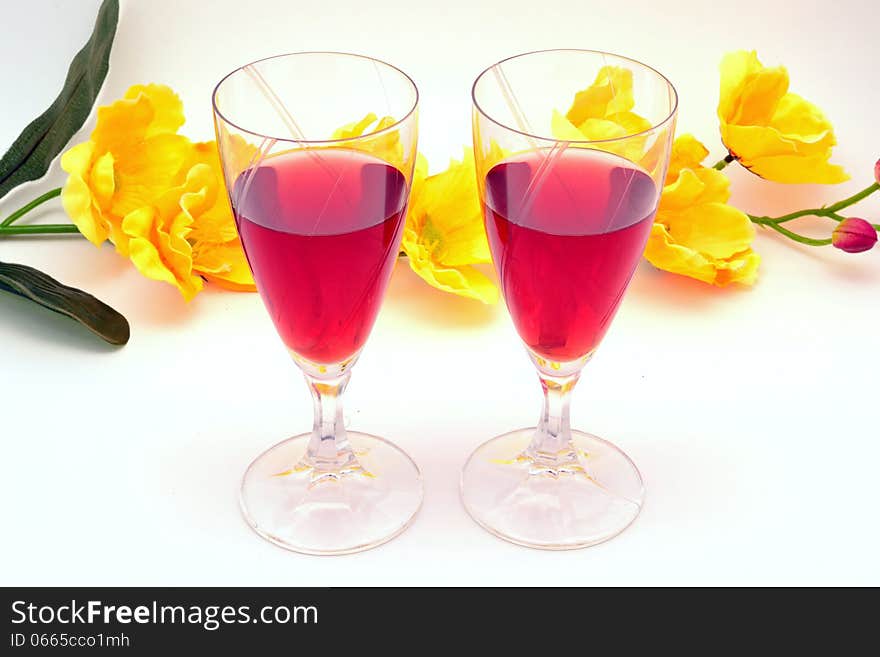 Strawberry liqueur in glass cups, with yellow floral background on white background