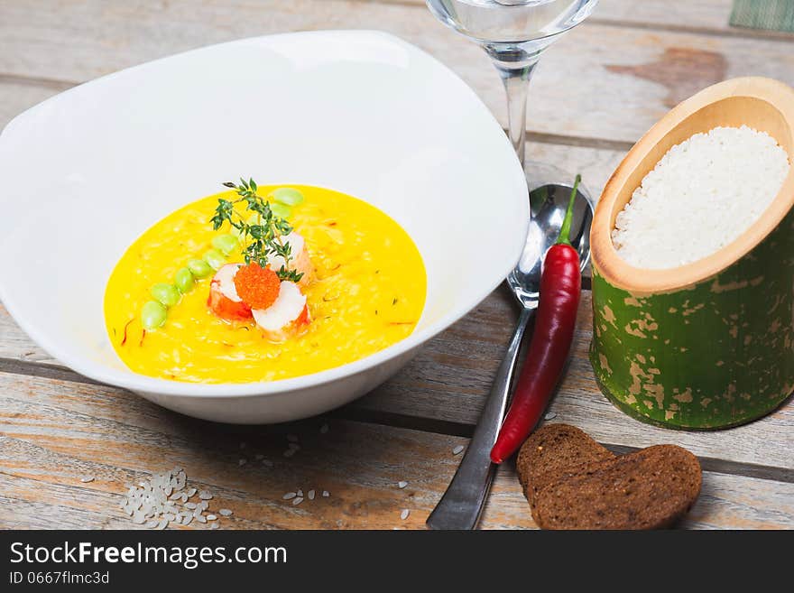 Serving of risotto in a deep plate on a wooden table with bread and decor. Serving of risotto in a deep plate on a wooden table with bread and decor