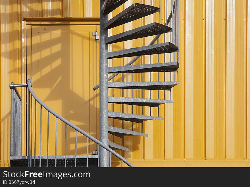 Yellow building with a spiral metal staircase. Emergency exit. Yellow building with a spiral metal staircase. Emergency exit