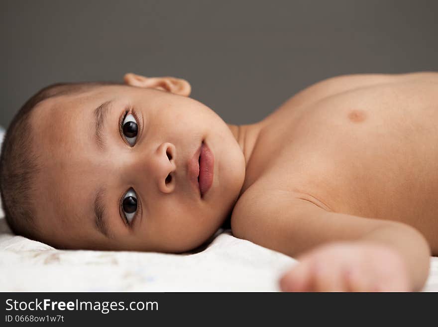 Indian baby looking and think with bright eyes over gray background in very short hair