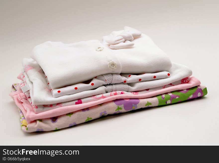 Baby clothes on a pink blanket on gray background. Baby clothes on a pink blanket on gray background