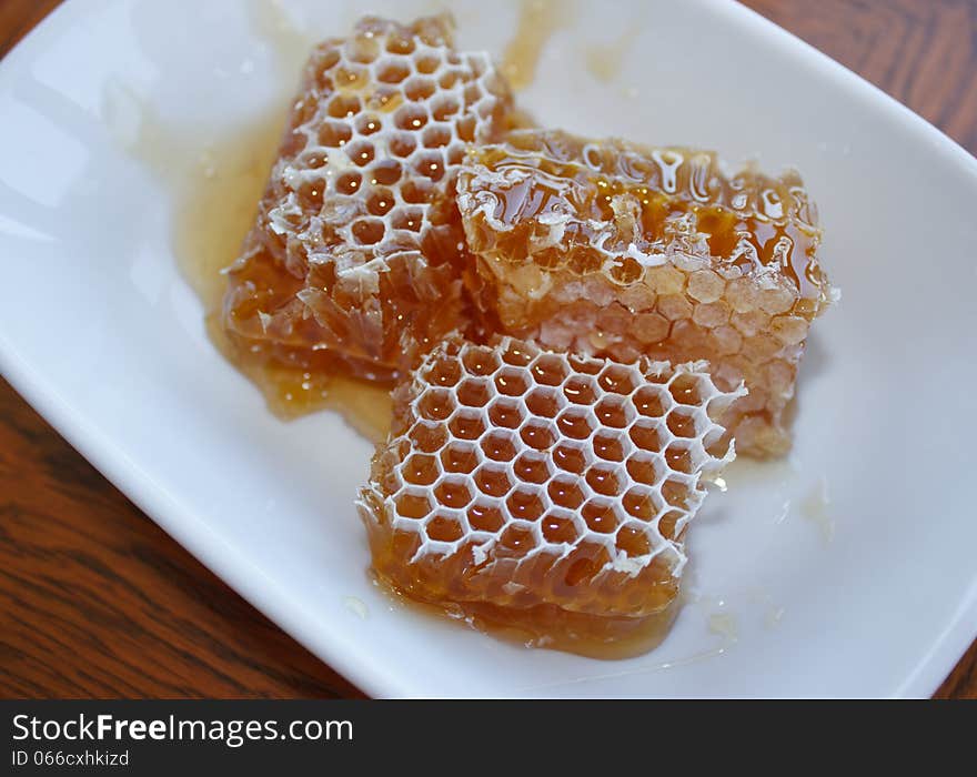 Honey in honeycomb in plate on wooden table