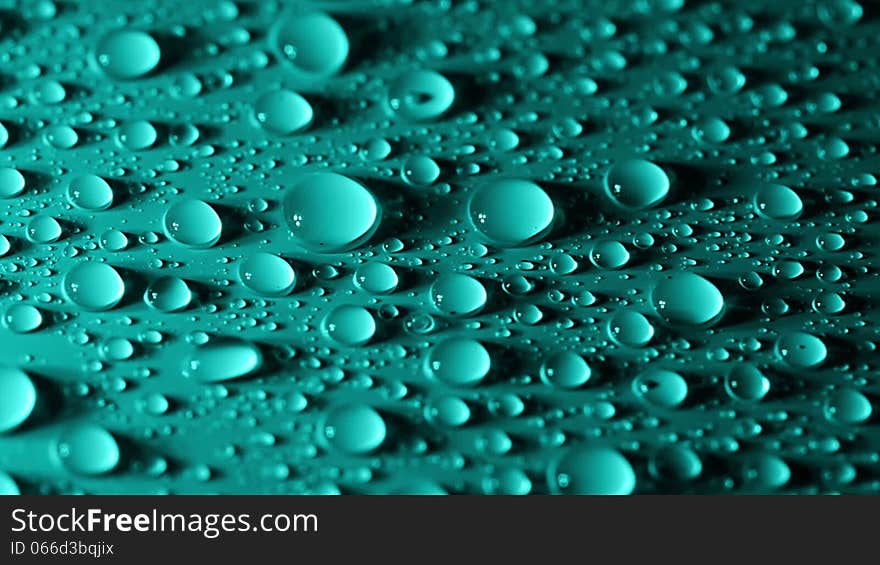 Many small water droplets on the turquoise surface. Large drops slide top, absorbing small drops. Many small water droplets on the turquoise surface. Large drops slide top, absorbing small drops