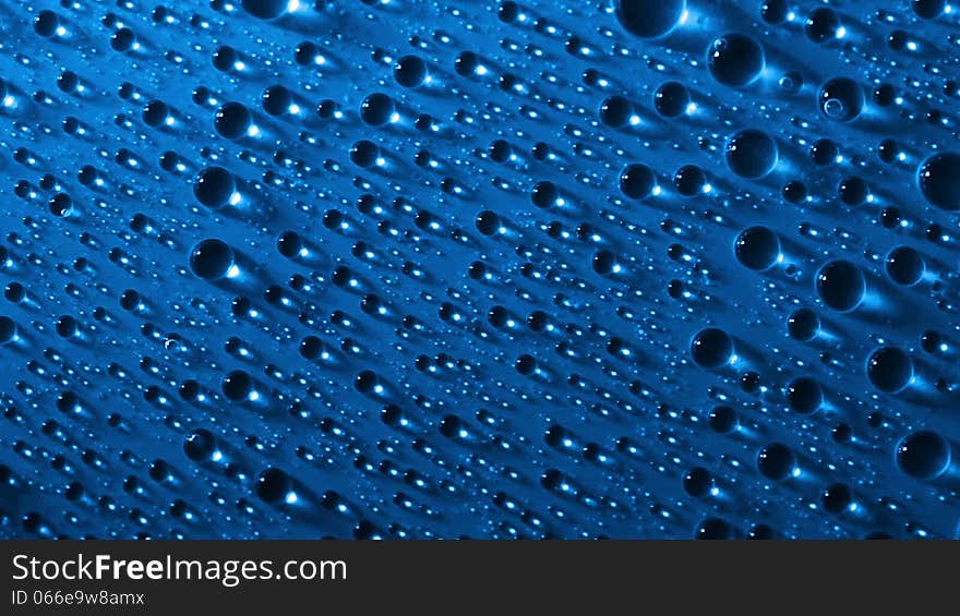 Blue background. Side lighting. Many water drops, highlights and shadows. Three large drops crawling down one after another. Blue background. Side lighting. Many water drops, highlights and shadows. Three large drops crawling down one after another