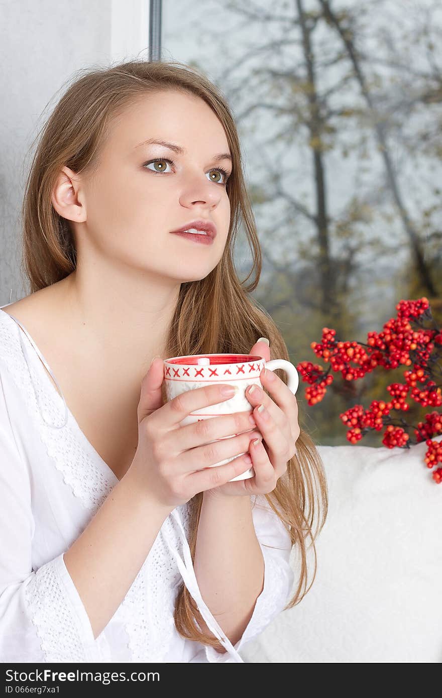 Girl holding cup and looking through window