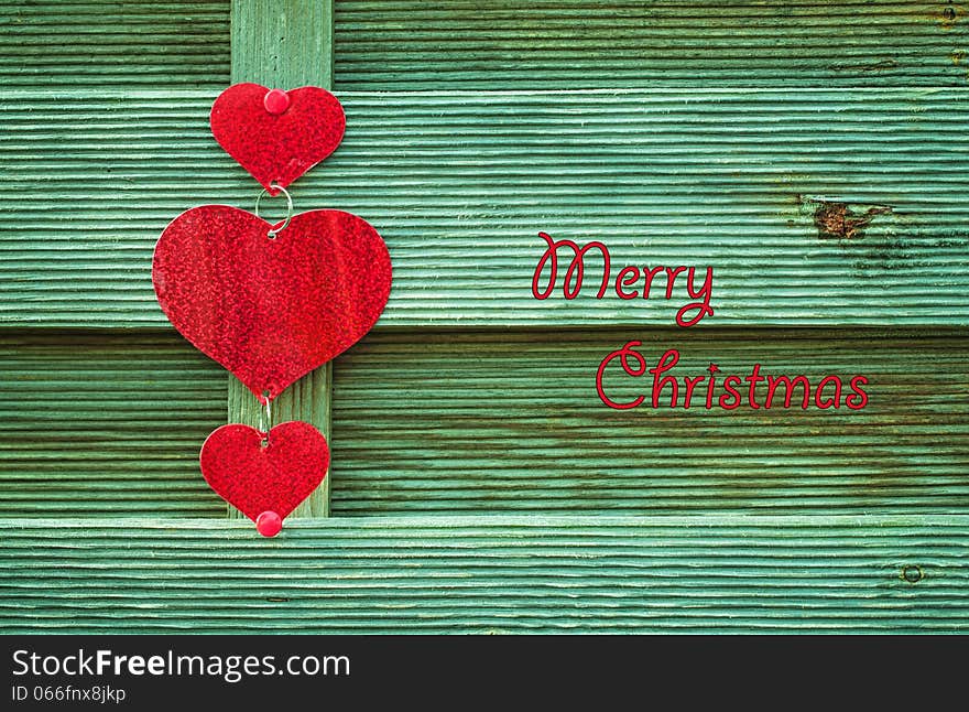 Red hearts on green wooden background with Merry christmas letters. Red hearts on green wooden background with Merry christmas letters