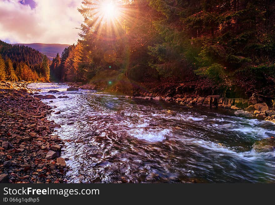 River flows by rocky shore near the autumn mountain forest