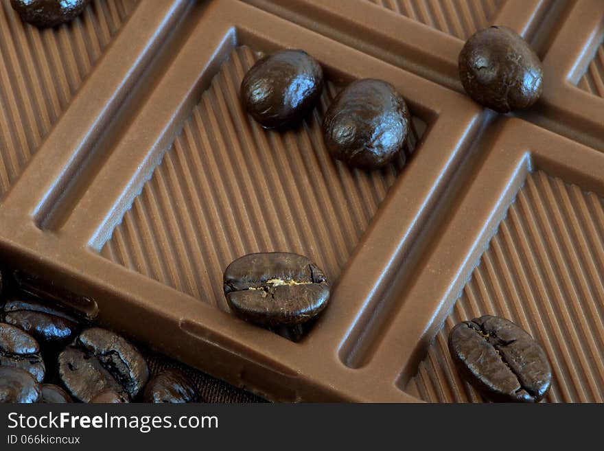 Coffee grains are on the bar of chocolate. Coffee grains are on the bar of chocolate