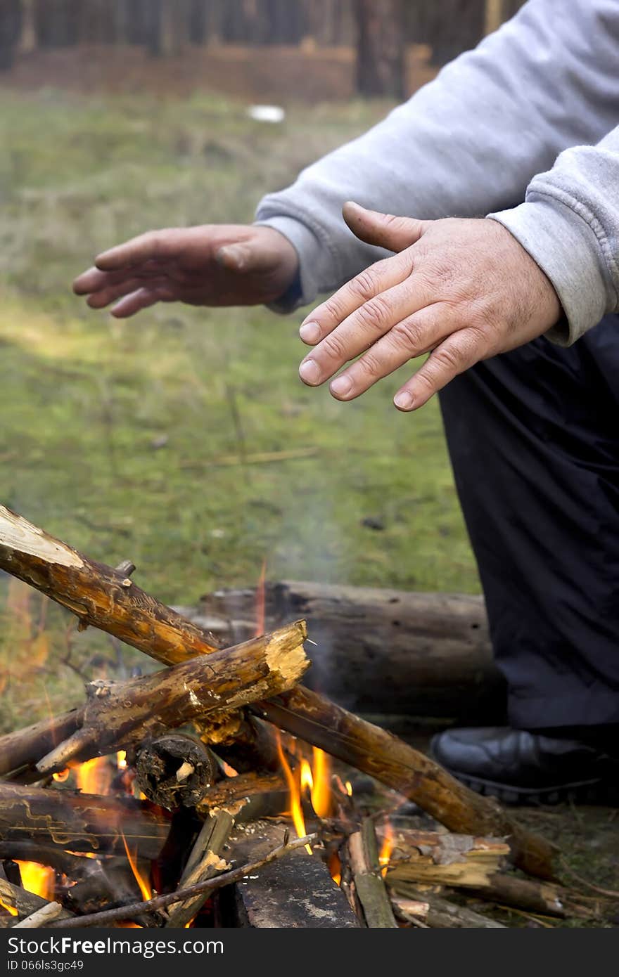 Hands heating over fireplace.