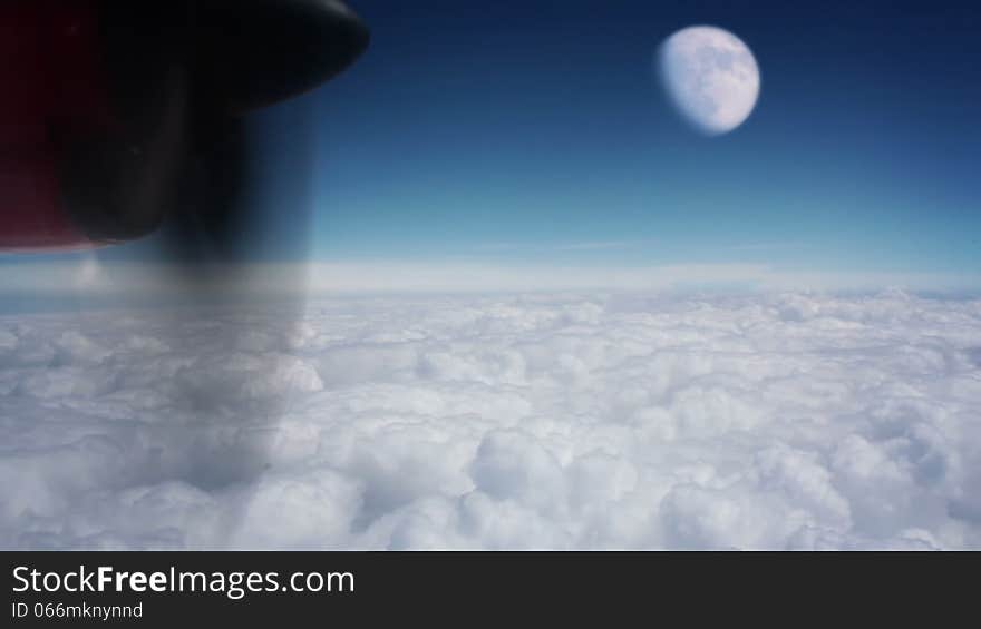 View from turboprop aircraft, which flies above the clouds. Bright sunny blue sky. Large moon. View from turboprop aircraft, which flies above the clouds. Bright sunny blue sky. Large moon