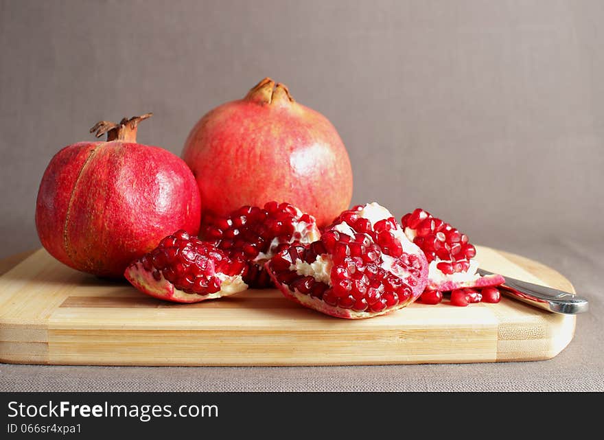 Pomegranate, divided into pieces on a cutting board. Pomegranate, divided into pieces on a cutting board