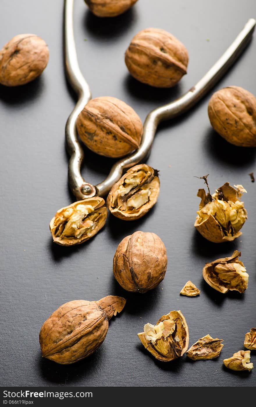 Walnuts and nutcracker on black glossy background