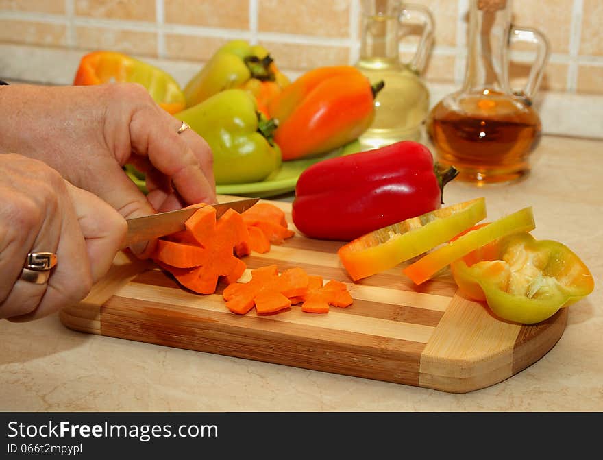 Woman cuts carrots on the cutting board. Woman cuts carrots on the cutting board