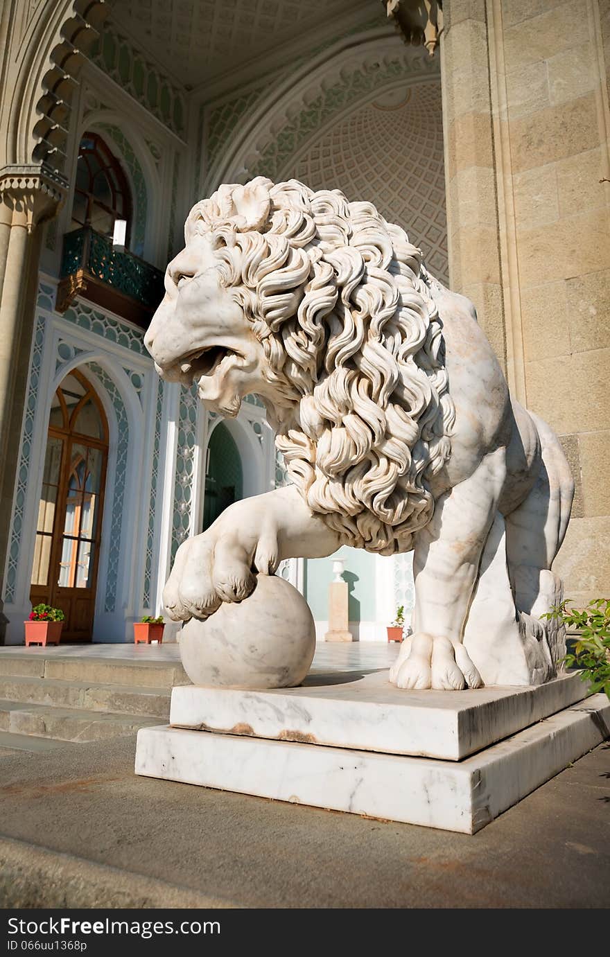 Sculpture of lion with a ball on a background of palace