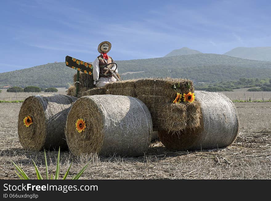 Cute scarecrow built atop a tractor with straw.