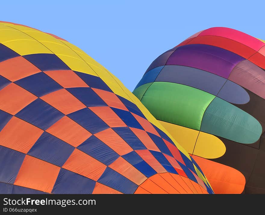 Two colorful hot air balloons being inflated. Blue sky in background. Two colorful hot air balloons being inflated. Blue sky in background.