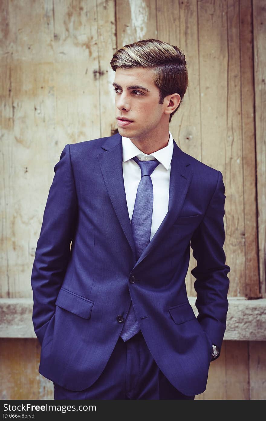 Portrait of an attractive young businessman in urban background wearing blue suit a necktie. Blonde hair