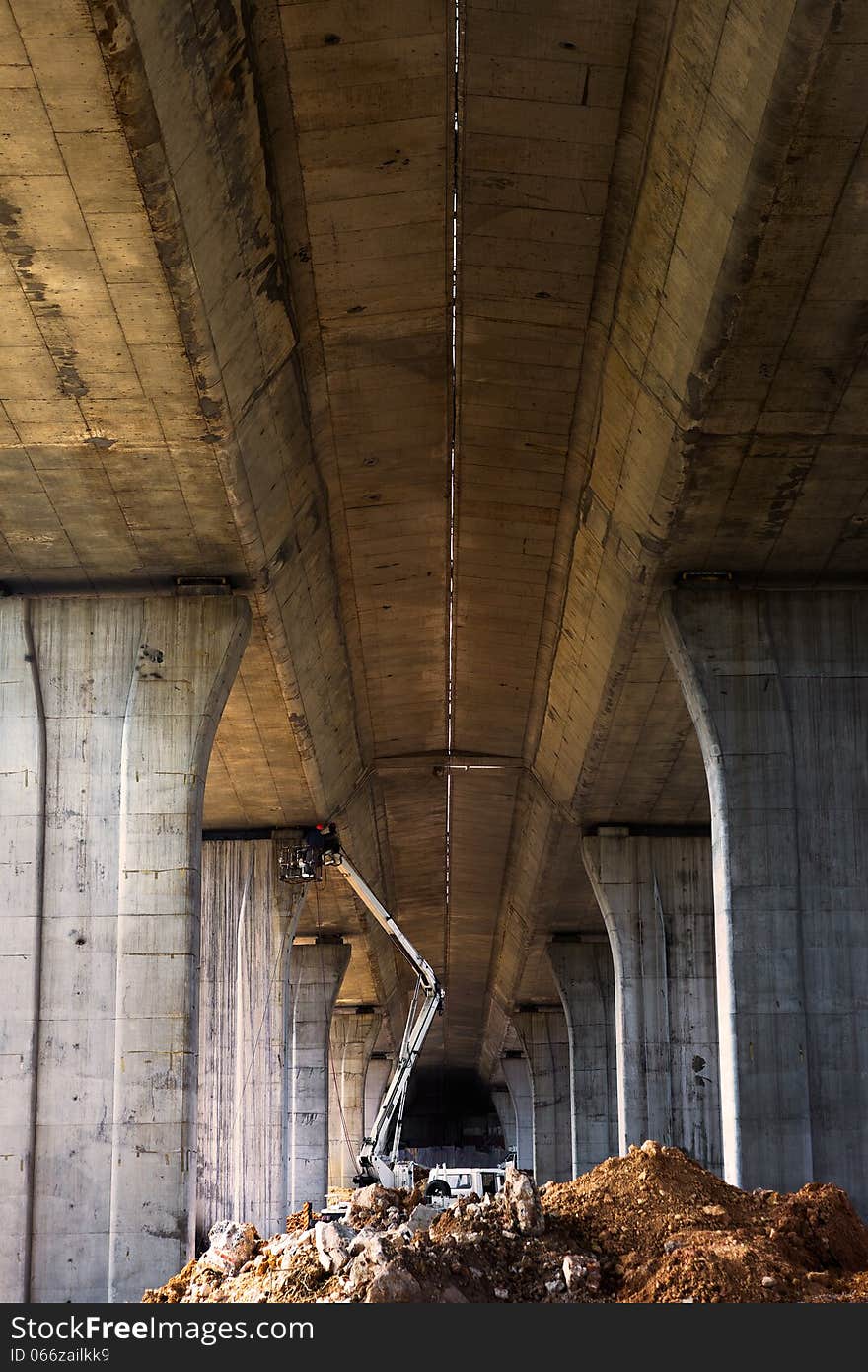 Workers maintaining bridge pier with construction machinery. Workers maintaining bridge pier with construction machinery