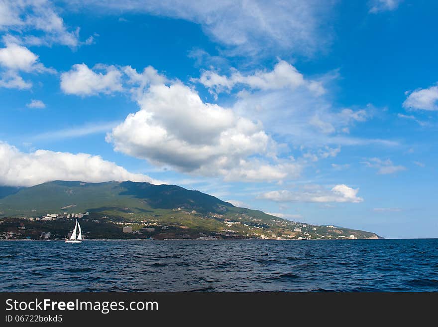 Yacht and blue water ocean. Shore the background. Yacht and blue water ocean. Shore the background