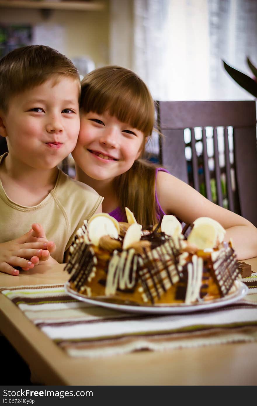 Children sit near a table and eat a cake. Children sit near a table and eat a cake