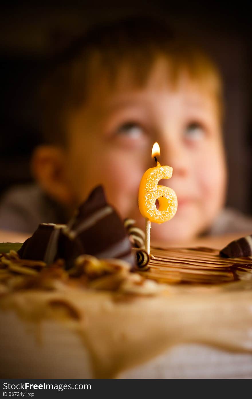 The boy looks at the birthday cake. The boy looks at the birthday cake