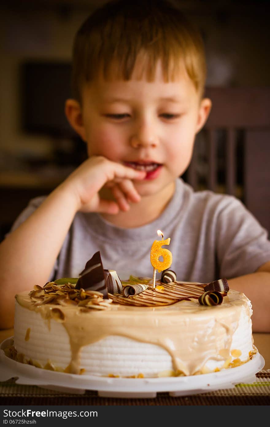 The boy looks at the birthday cake. The boy looks at the birthday cake